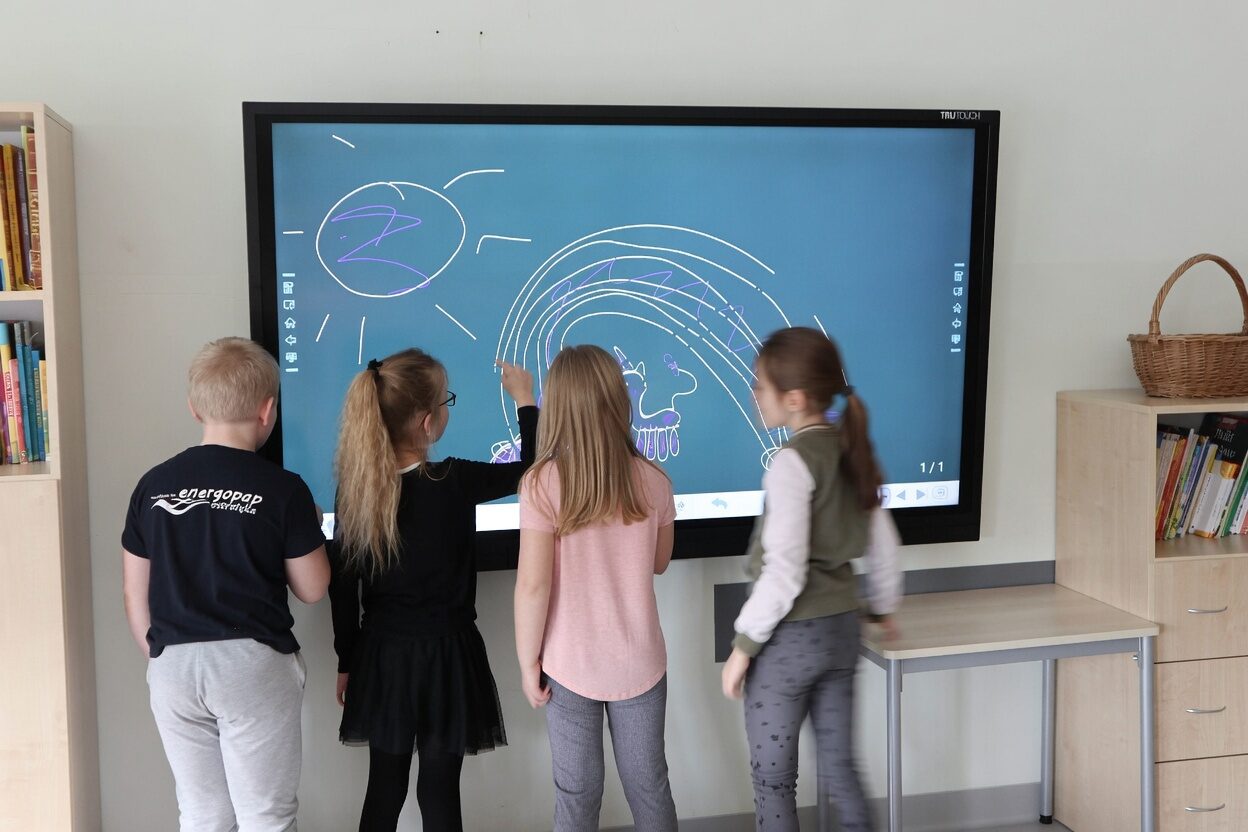 Students gathered at an interactive smartboard in a classroom